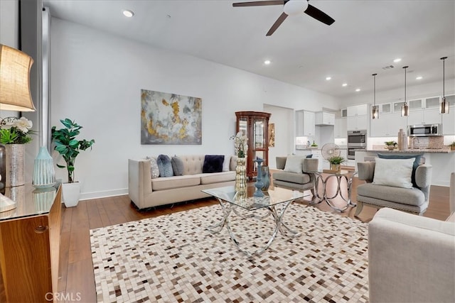 living room featuring ceiling fan and dark hardwood / wood-style floors