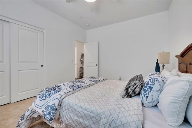 bedroom with ceiling fan, light carpet, and a closet