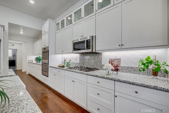 kitchen with light stone counters, tasteful backsplash, white cabinets, stainless steel appliances, and dark hardwood / wood-style floors