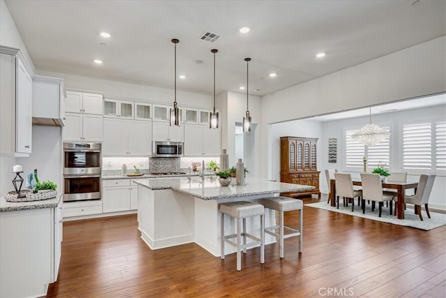 kitchen with white cabinetry, light stone countertops, stainless steel appliances, and dark hardwood / wood-style flooring