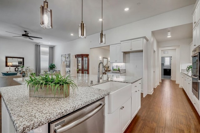 kitchen featuring dishwasher, a kitchen island with sink, white cabinets, hanging light fixtures, and ceiling fan