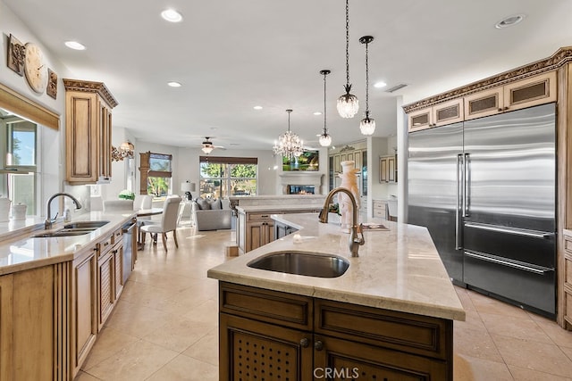 kitchen featuring sink, an island with sink, hanging light fixtures, and stainless steel built in refrigerator