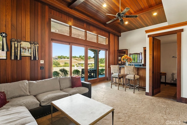 carpeted living room featuring wooden walls, ceiling fan, and wooden ceiling