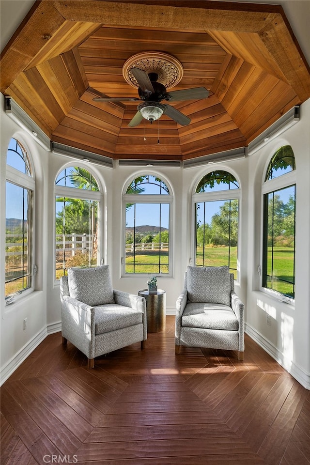 unfurnished sunroom featuring wood ceiling and ceiling fan