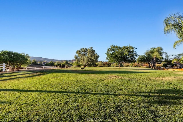 surrounding community with a rural view, a mountain view, and a lawn