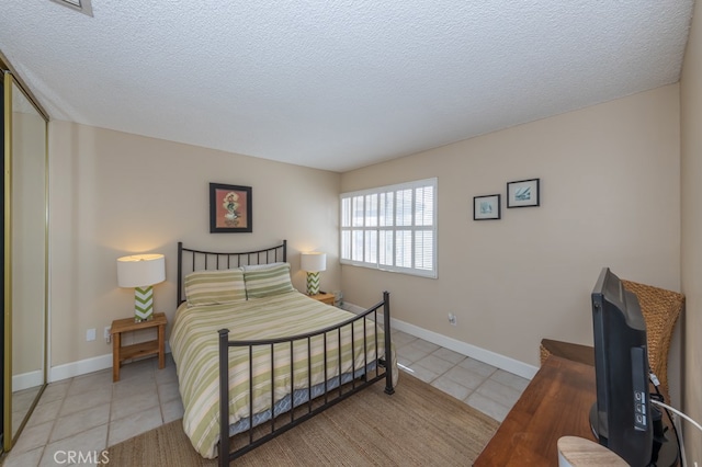 bedroom with a textured ceiling, light tile patterned flooring, and baseboards