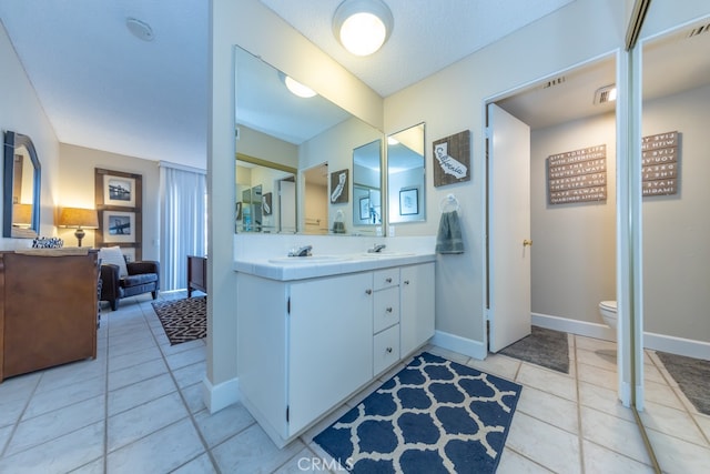 full bath featuring toilet, a sink, a textured ceiling, tile patterned flooring, and baseboards