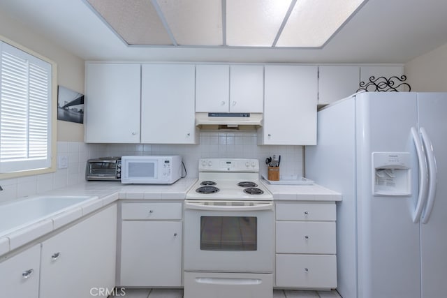 kitchen with tile countertops, white appliances, white cabinetry, and under cabinet range hood