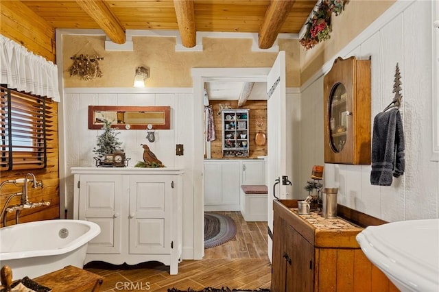 bathroom with beam ceiling, wood ceiling, wooden walls, and a tub