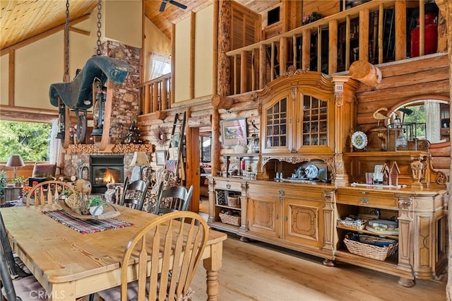 dining space with wooden ceiling, rustic walls, high vaulted ceiling, and light hardwood / wood-style flooring