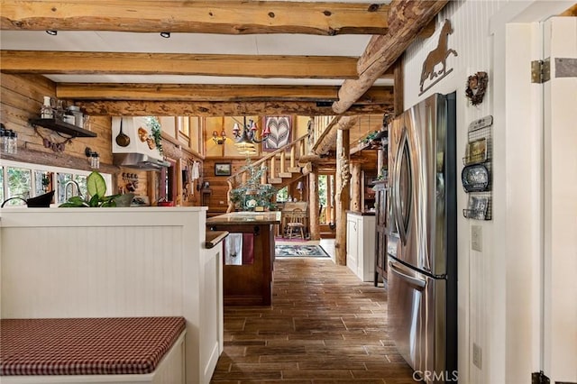 kitchen with stainless steel fridge, wooden walls, beamed ceiling, and plenty of natural light