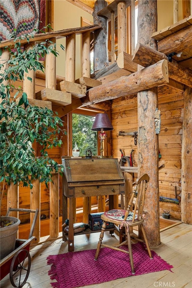 misc room featuring wood walls, light hardwood / wood-style floors, and a high ceiling