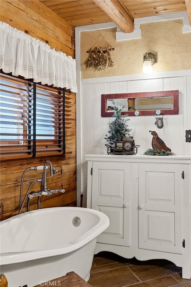 bathroom with beam ceiling, wood ceiling, a tub, and wood walls