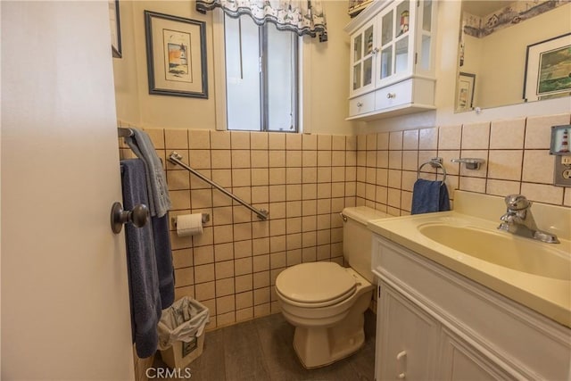 bathroom with toilet, vanity, tile walls, and wood-type flooring