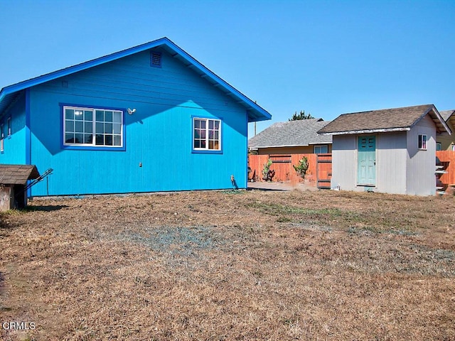 back of property featuring an outbuilding, a shed, and fence