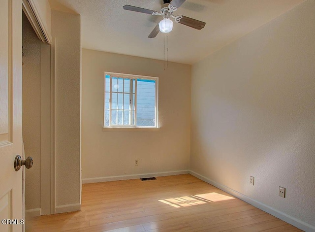 interior space featuring light wood-type flooring, visible vents, baseboards, and ceiling fan