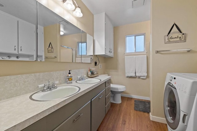 bathroom featuring washer / clothes dryer, vanity, walk in shower, toilet, and hardwood / wood-style floors