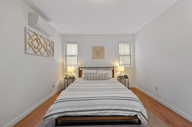 bedroom with light hardwood / wood-style flooring and a wall mounted air conditioner