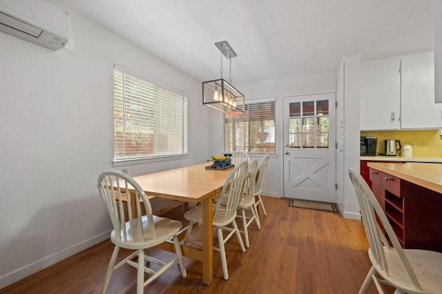 dining room with an AC wall unit, a chandelier, and light hardwood / wood-style floors