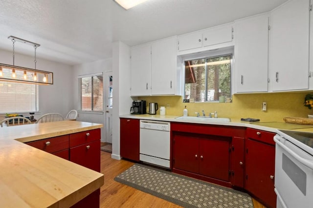 kitchen featuring pendant lighting, sink, white appliances, tasteful backsplash, and light hardwood / wood-style flooring