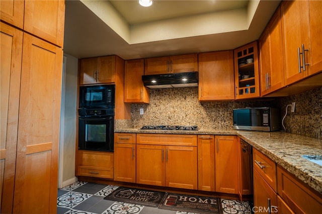 kitchen with light stone countertops, tasteful backsplash, and black appliances