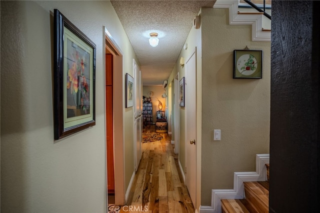 corridor featuring a textured ceiling and light hardwood / wood-style floors