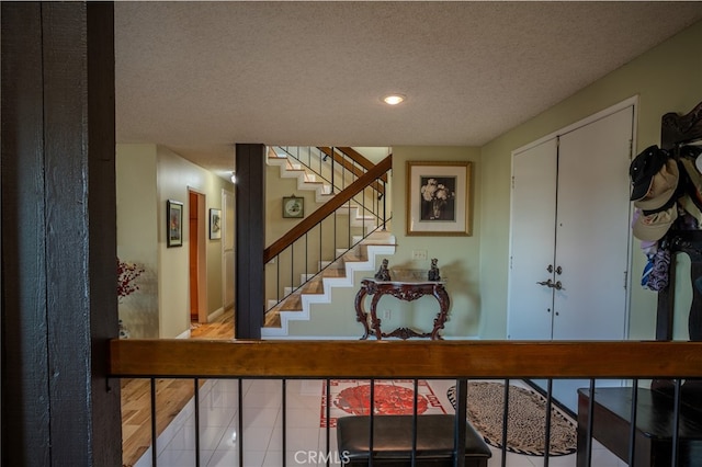 stairs with a textured ceiling and wood-type flooring