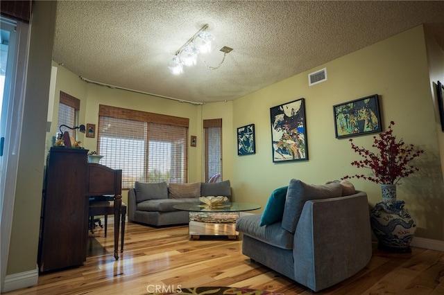 living room featuring a notable chandelier, a textured ceiling, and hardwood / wood-style floors