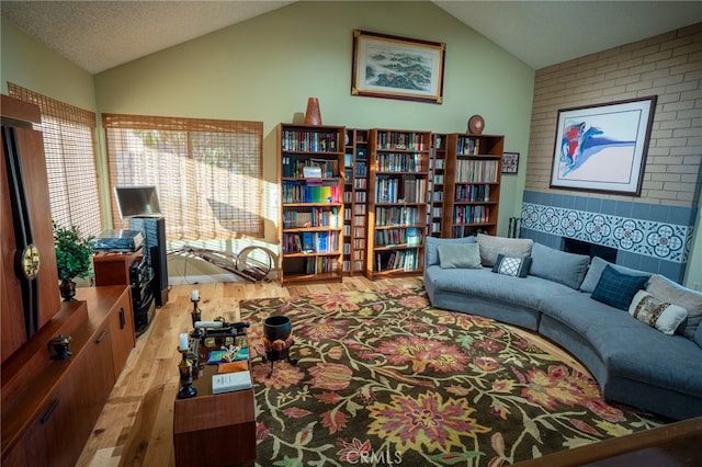 living room featuring light wood-type flooring, a textured ceiling, and lofted ceiling