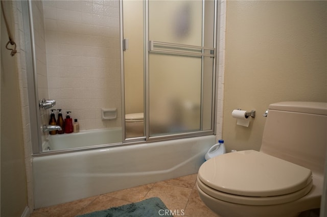 bathroom featuring combined bath / shower with glass door, toilet, and tile patterned floors