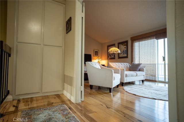 living room with a textured ceiling, light hardwood / wood-style floors, and vaulted ceiling