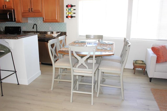 kitchen featuring decorative backsplash, a breakfast bar, stainless steel appliances, and light hardwood / wood-style floors