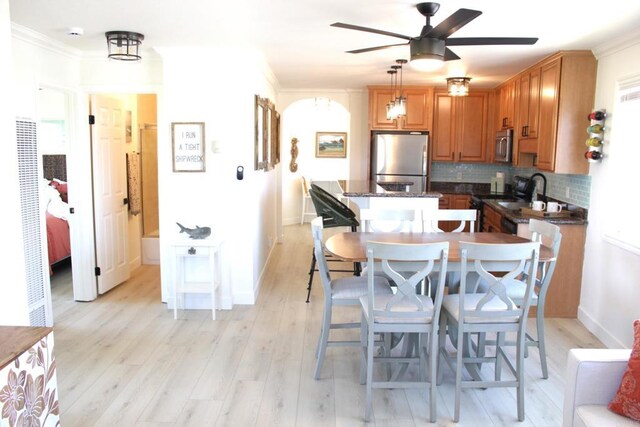 kitchen featuring appliances with stainless steel finishes, backsplash, crown molding, light hardwood / wood-style flooring, and hanging light fixtures