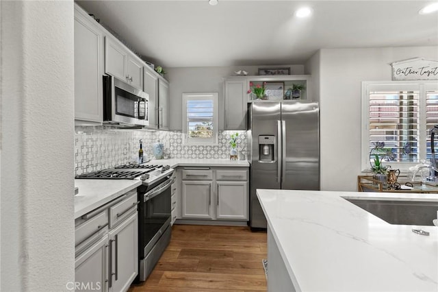 kitchen featuring sink, light stone counters, appliances with stainless steel finishes, dark hardwood / wood-style floors, and backsplash