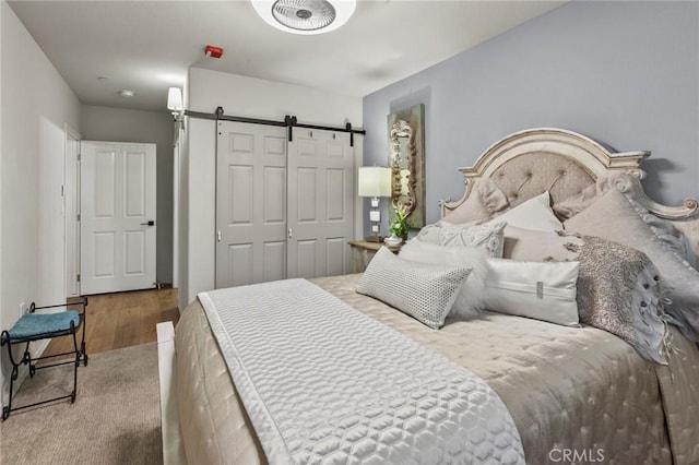 bedroom featuring a closet, wood-type flooring, and a barn door