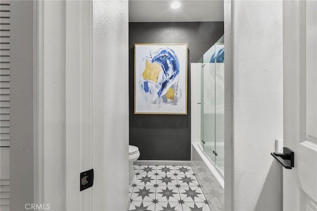 bathroom featuring bath / shower combo with glass door and toilet