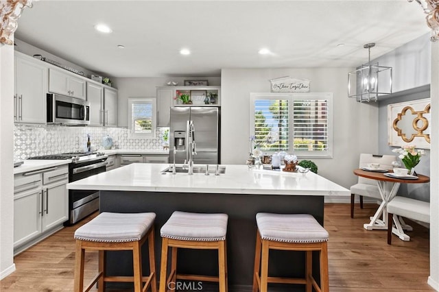 kitchen with hanging light fixtures, a kitchen island, light hardwood / wood-style floors, and appliances with stainless steel finishes