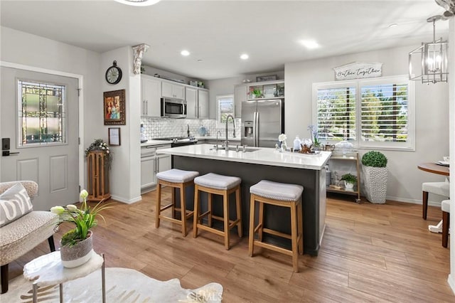 kitchen featuring sink, a center island with sink, plenty of natural light, stainless steel appliances, and decorative backsplash