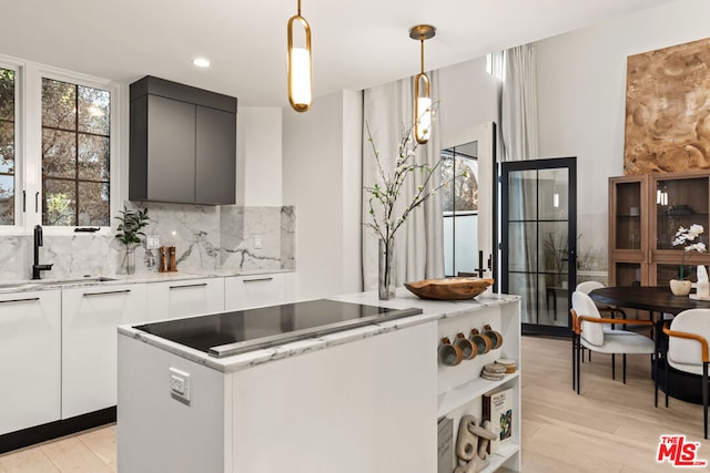 kitchen featuring sink, white cabinetry, stove, decorative backsplash, and hanging light fixtures