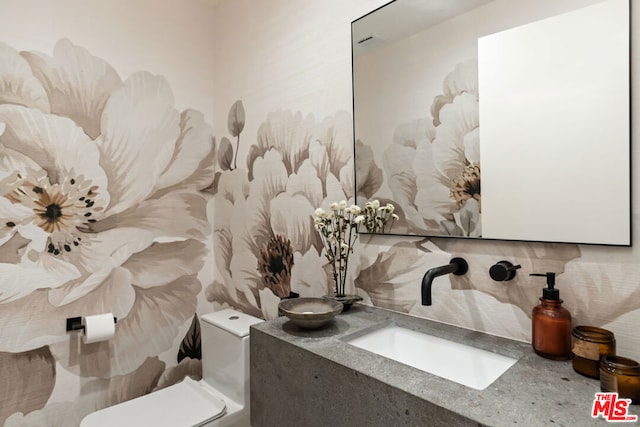 bathroom with toilet, vanity, and decorative backsplash