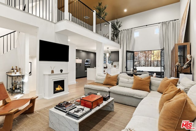 living room with a high ceiling, a notable chandelier, and light hardwood / wood-style flooring