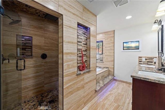 bathroom with vanity and shower with separate bathtub