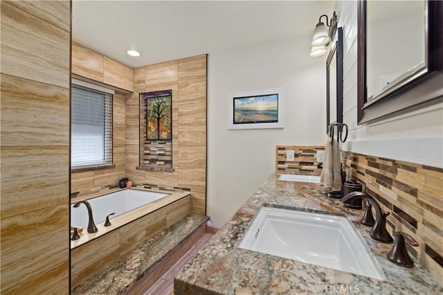 bathroom with hardwood / wood-style floors, vanity, and tiled tub