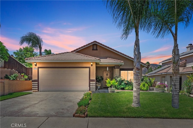 view of front of home with an attached garage, a tile roof, driveway, stucco siding, and a front yard