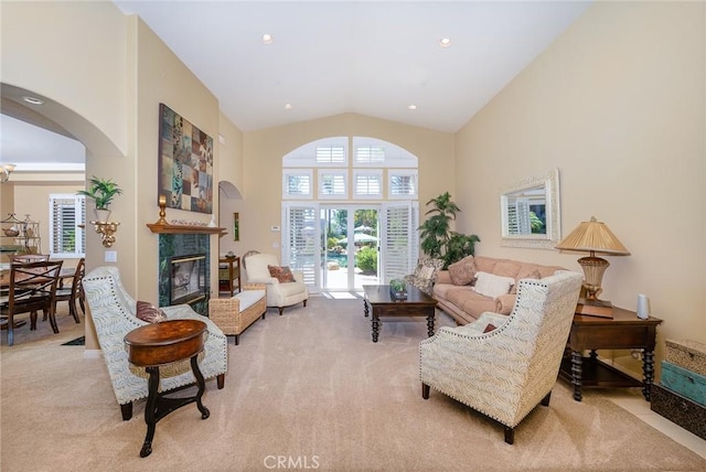 living room with light carpet, a high end fireplace, and high vaulted ceiling