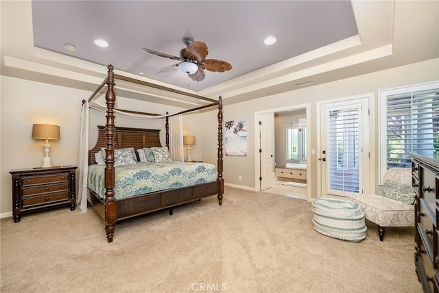 carpeted bedroom featuring connected bathroom, a tray ceiling, and ceiling fan