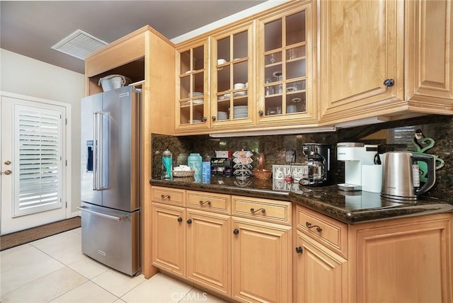 kitchen featuring decorative backsplash, high end fridge, light tile patterned flooring, and dark stone counters