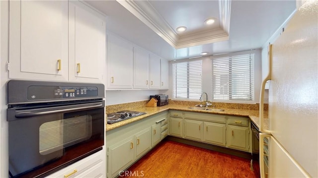 kitchen featuring a raised ceiling, sink, black appliances, hardwood / wood-style floors, and green cabinets