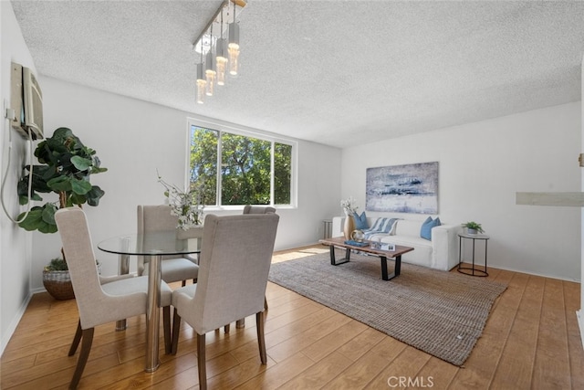 dining space with hardwood / wood-style floors and a textured ceiling