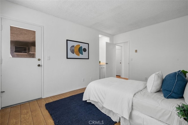 bedroom with a textured ceiling and light wood-type flooring